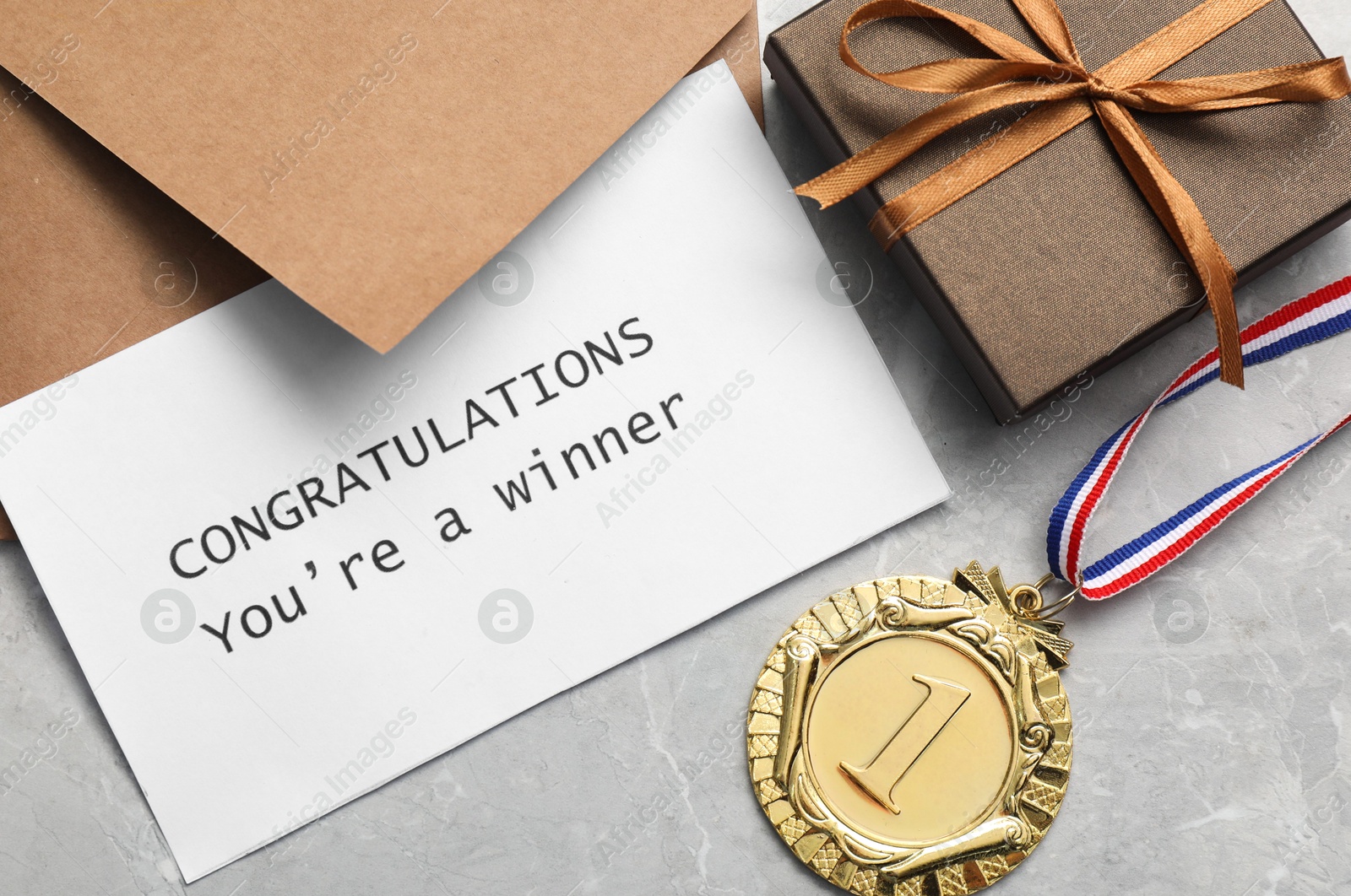 Photo of Card with phrase Congratulations You`re Winner, envelope, gift box and golden medal on grey marble table, flat lay