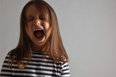 Photo of Scared little girl screaming on grey background. Space for text