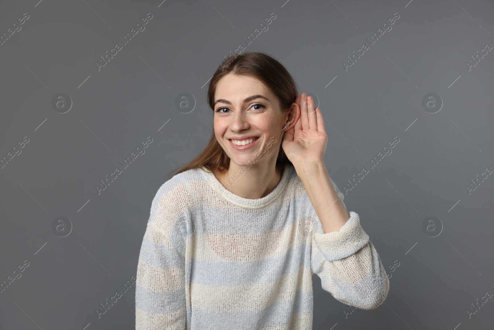 Photo of Woman showing hand to ear gesture on grey background