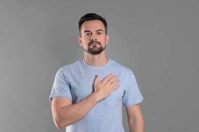 Photo of Man making promise on grey background. Oath gesture