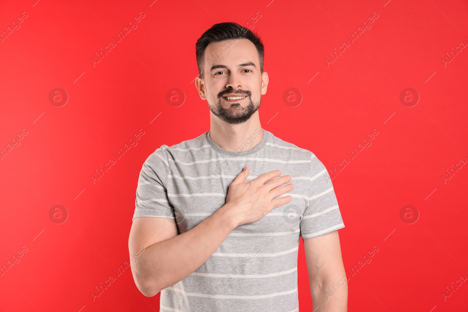 Photo of Man making promise on red background. Oath gesture