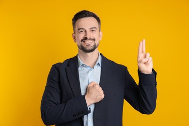 Photo of Man showing oath gesture on orange background. Making promise