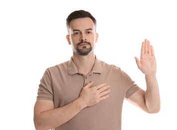 Photo of Man making promise with raised hand on white background. Oath gesture