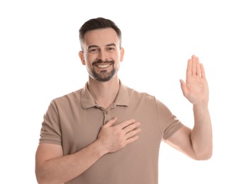 Photo of Man making promise with raised hand on white background. Oath gesture