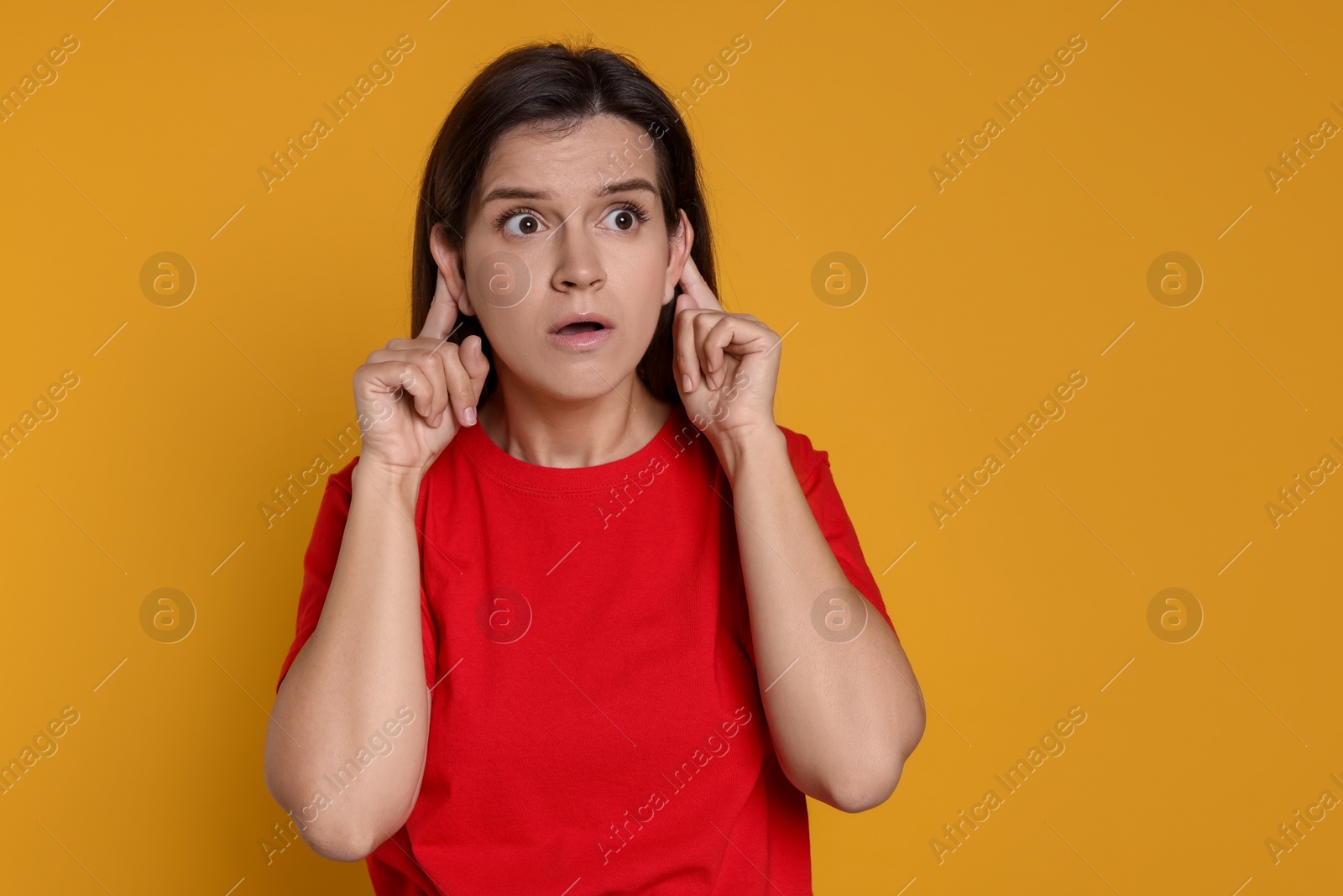 Photo of Woman showing hand to ear gesture on orange background