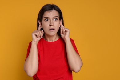 Photo of Woman showing hand to ear gesture on orange background