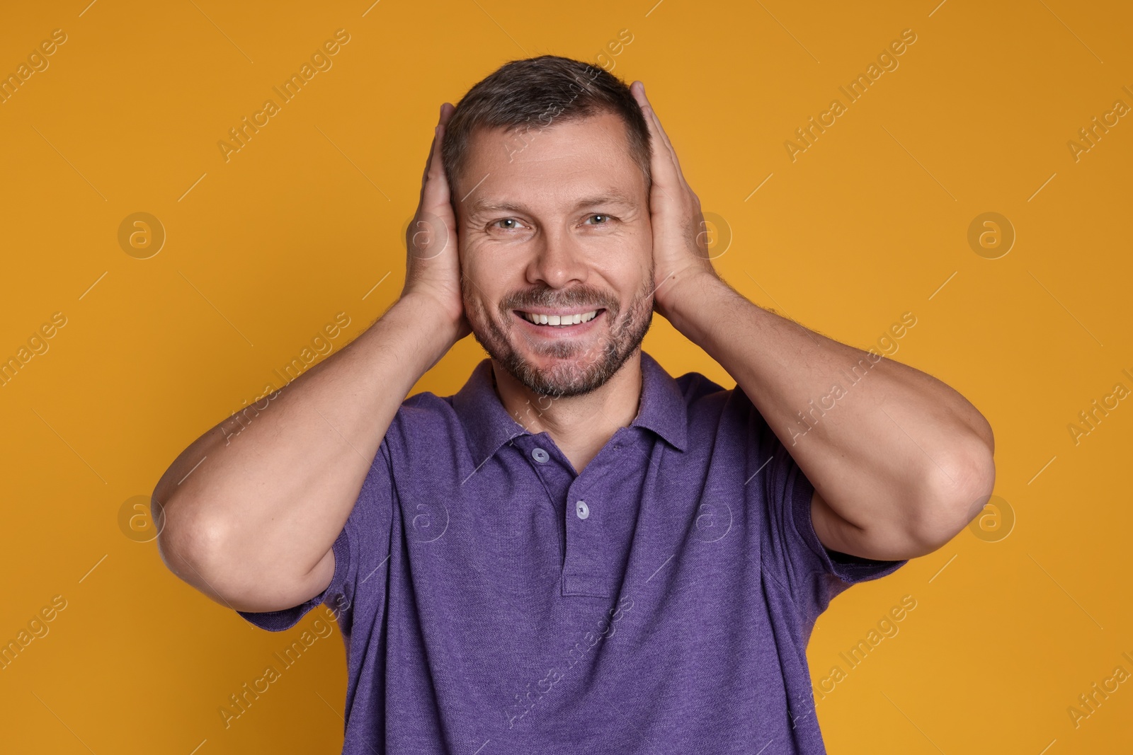 Photo of Man covering his ears on orange background