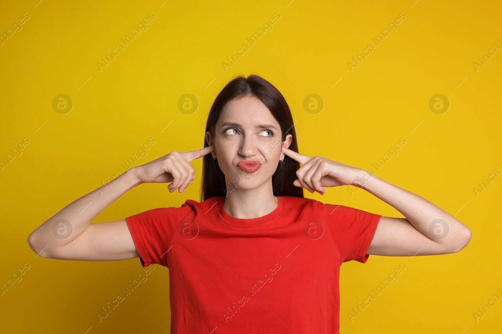 Photo of Woman covering her ears with fingers on orange background