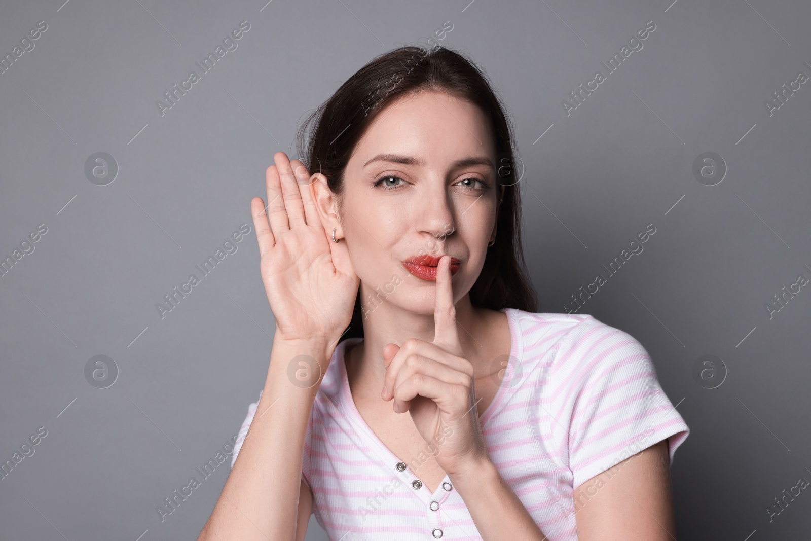 Photo of Woman showing hand to ear gesture on grey background