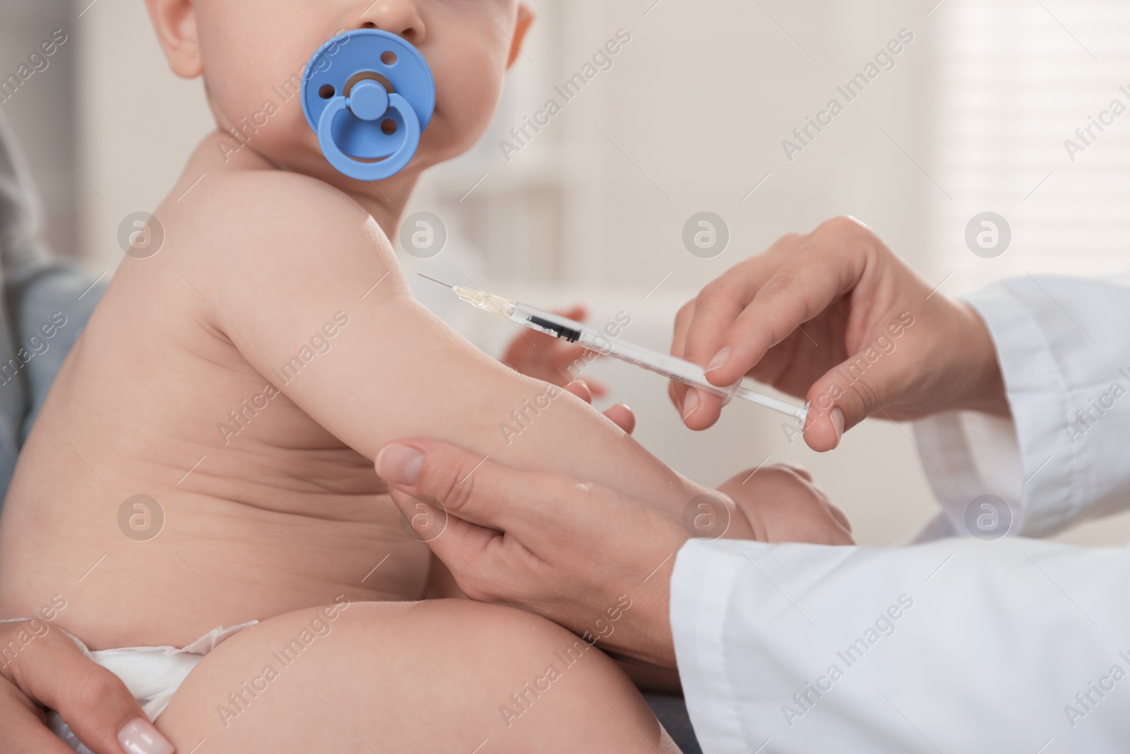 Photo of Pediatrician vaccinating little baby in clinic, closeup