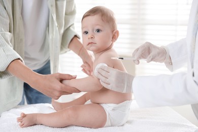 Photo of Pediatrician vaccinating little baby in clinic, closeup