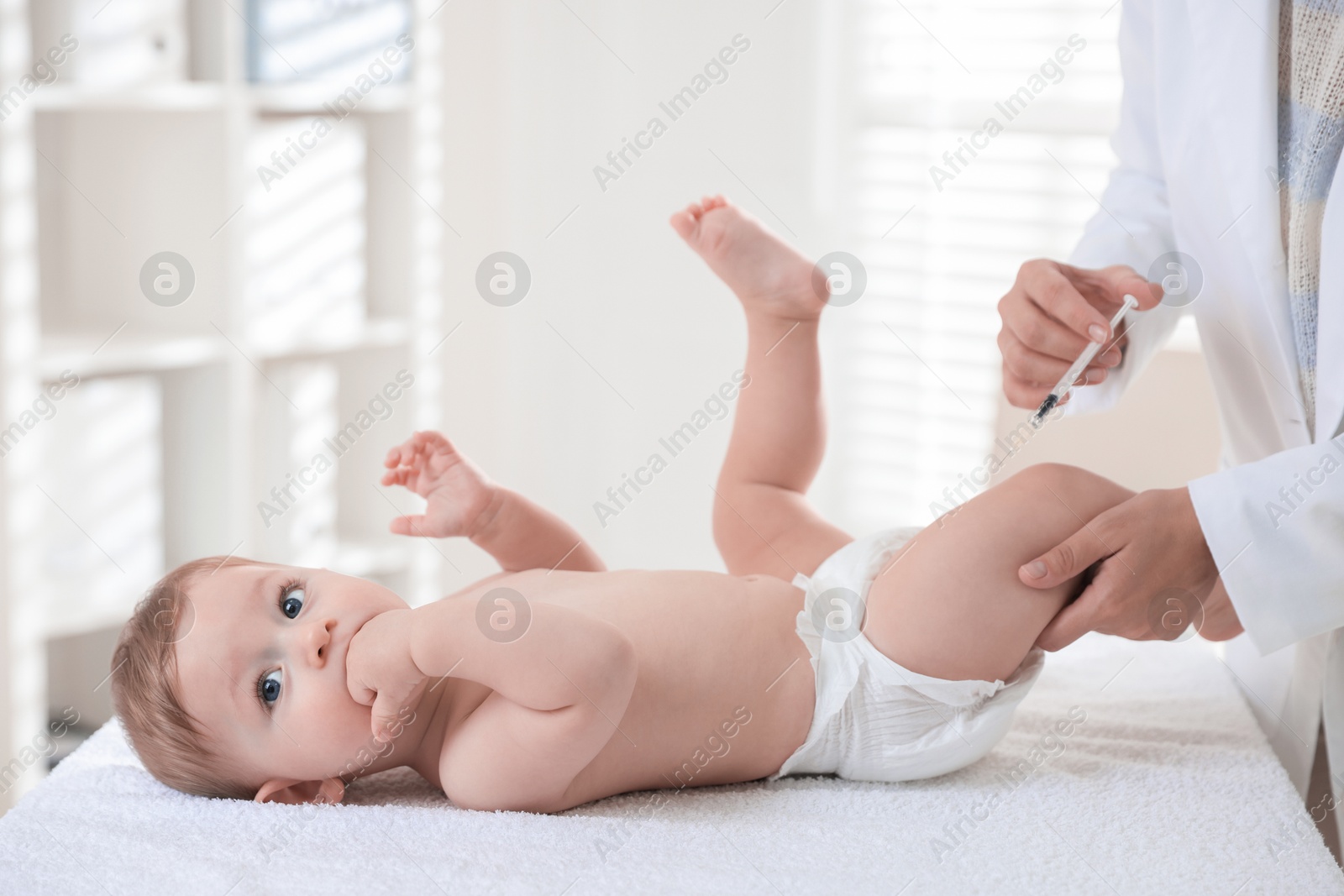 Photo of Pediatrician vaccinating little baby in clinic, closeup