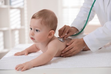 Photo of Pediatrician examining little child with stethoscope in clinic, closeup. Checking baby's health