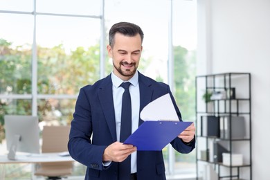 Photo of Smiling banker working with clipboard in office