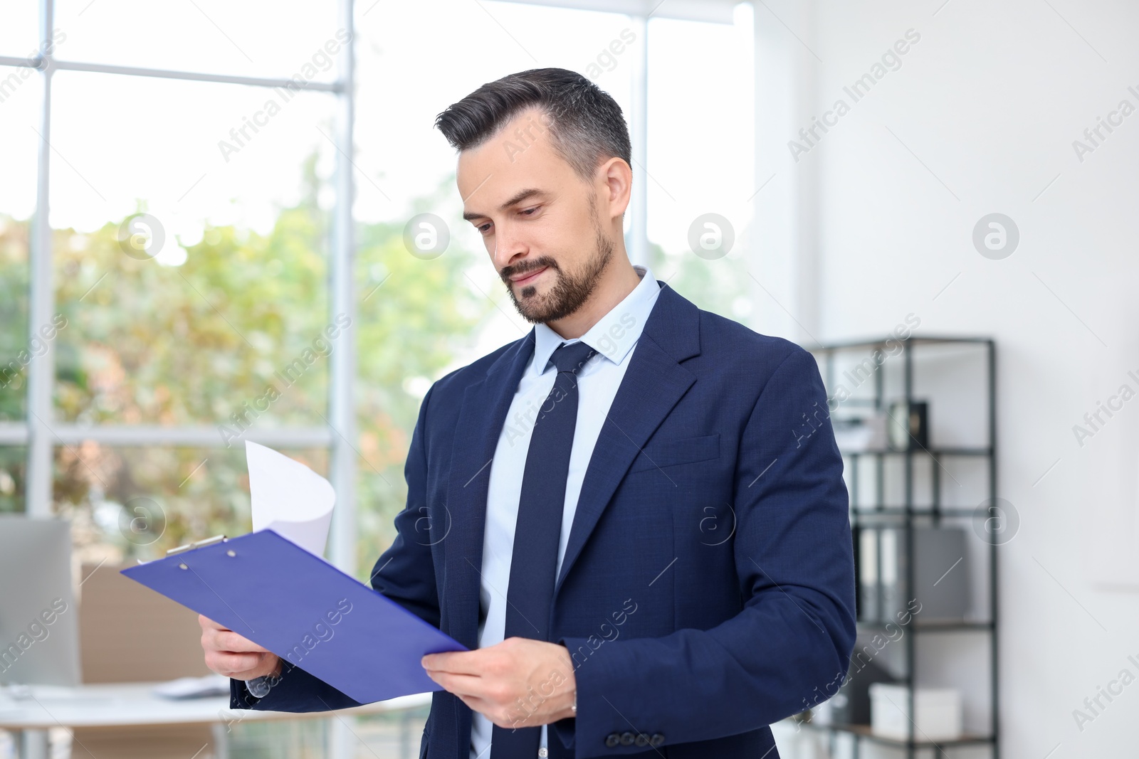 Photo of Handsome banker working with clipboard in office