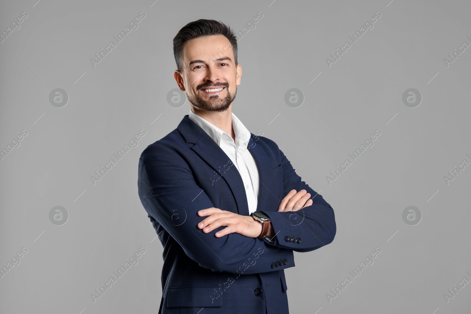 Photo of Portrait of smiling banker with crossed arms on grey background