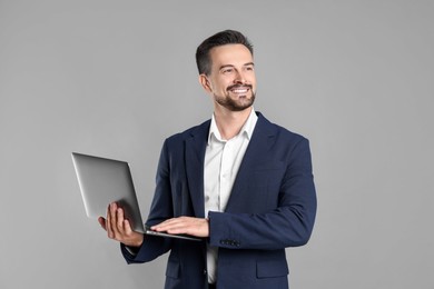 Photo of Portrait of smiling banker with laptop on grey background