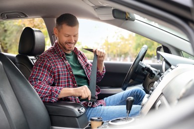 Photo of Man fastening seat belt in modern car