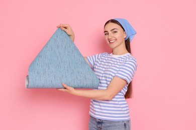 Photo of Young decorator with roll of wallpaper on pink background