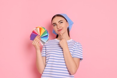 Photo of Portrait of young decorator with color palettes on pink background