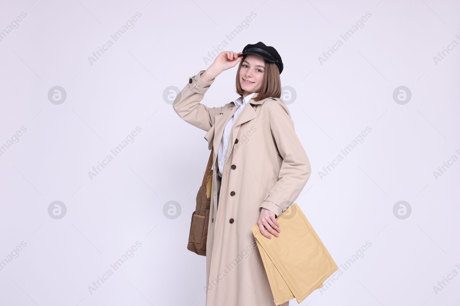 Photo of Happy postwoman with bag and envelopes on white background