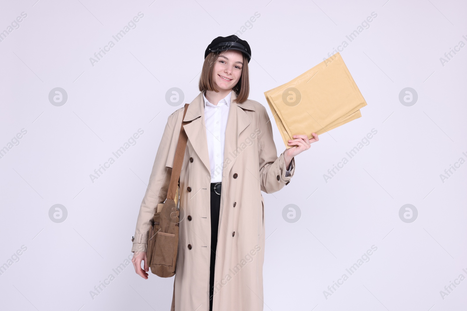 Photo of Happy postwoman with bag and envelopes on white background