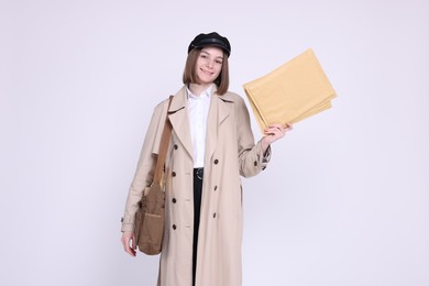 Photo of Happy postwoman with bag and envelopes on white background