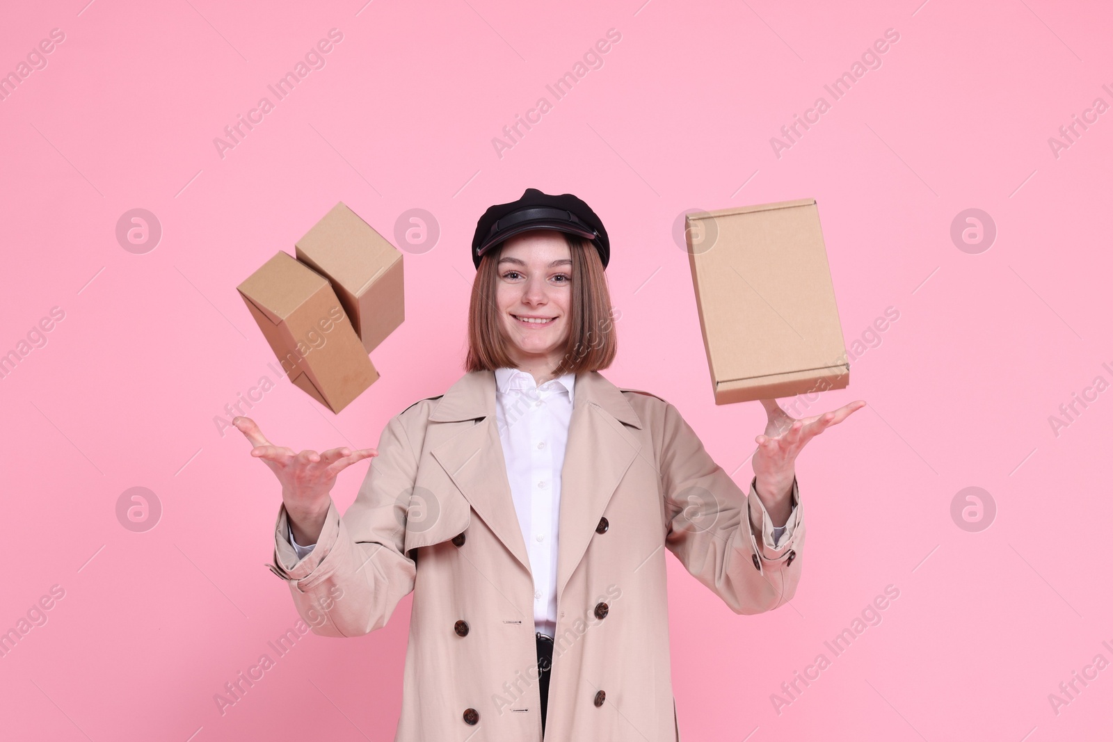 Photo of Happy postwoman throwing parcels on pink background