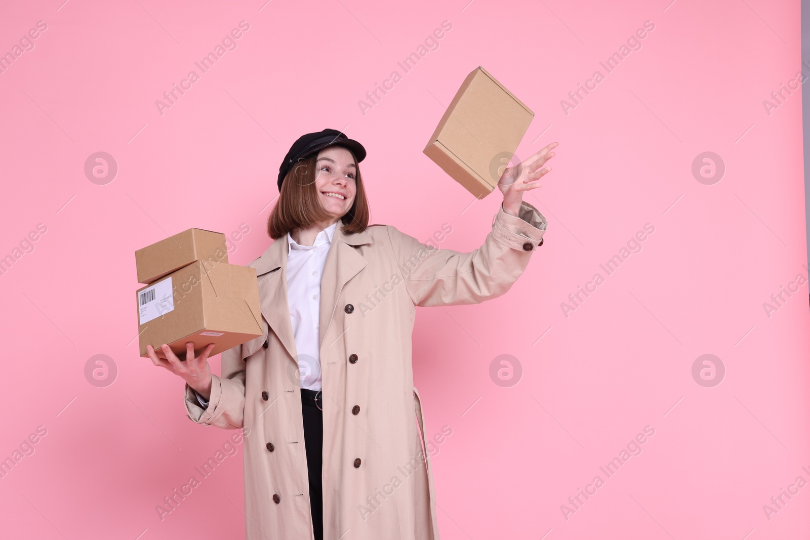 Photo of Happy postwoman with parcels on pink background