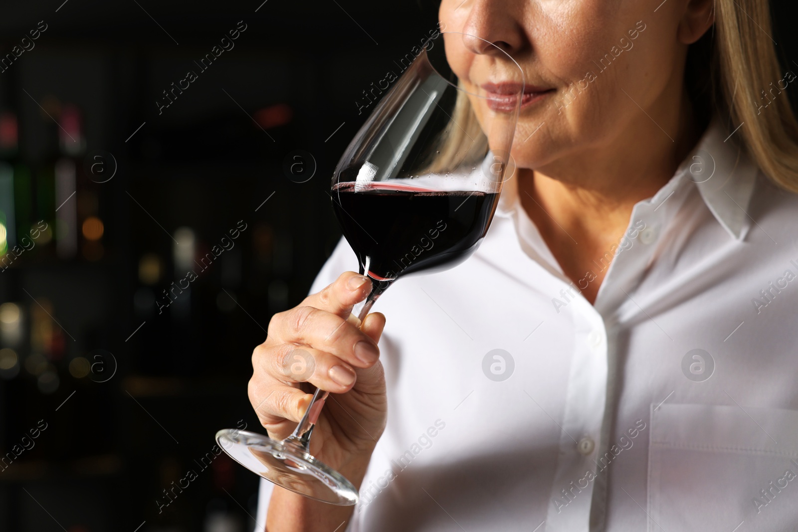 Photo of Professional sommelier tasting red wine indoors, closeup