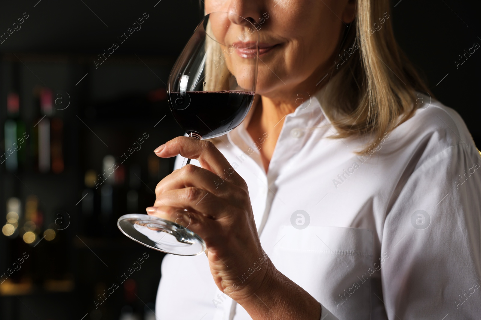 Photo of Professional sommelier tasting red wine indoors, closeup