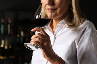 Photo of Professional sommelier tasting red wine indoors, closeup