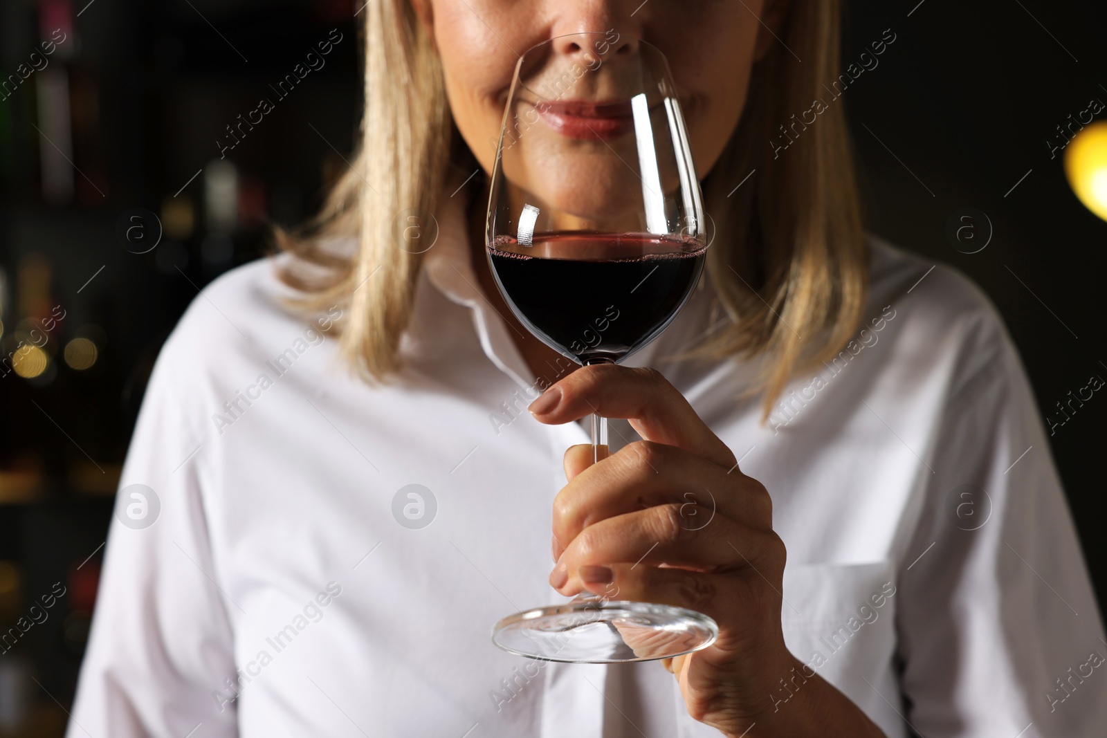 Photo of Professional sommelier tasting red wine indoors, closeup