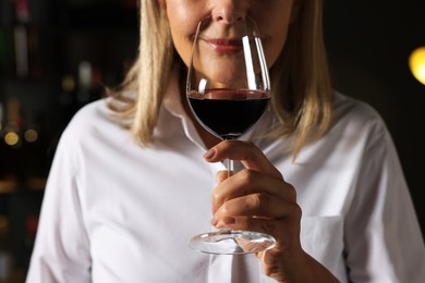 Photo of Professional sommelier tasting red wine indoors, closeup