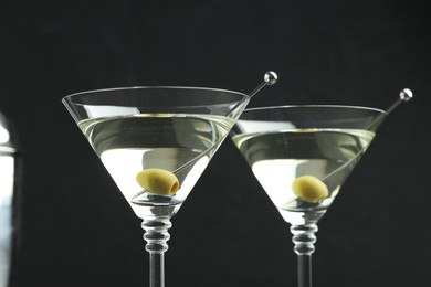 Photo of Martini cocktail with olives in glasses on black background, closeup