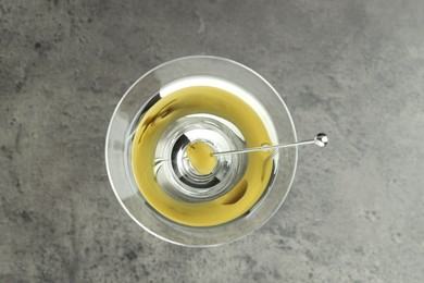 Photo of Martini cocktail with olive in glass on grey table, top view