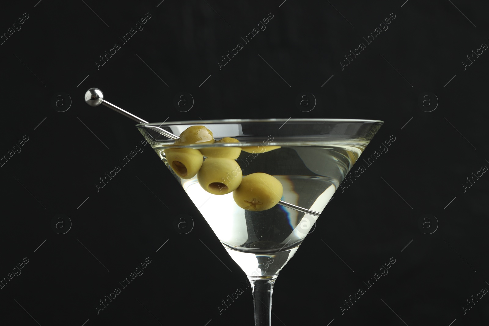 Photo of Martini cocktail with olives in glass on black background, closeup