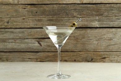 Photo of Martini cocktail with olives in glass on light table