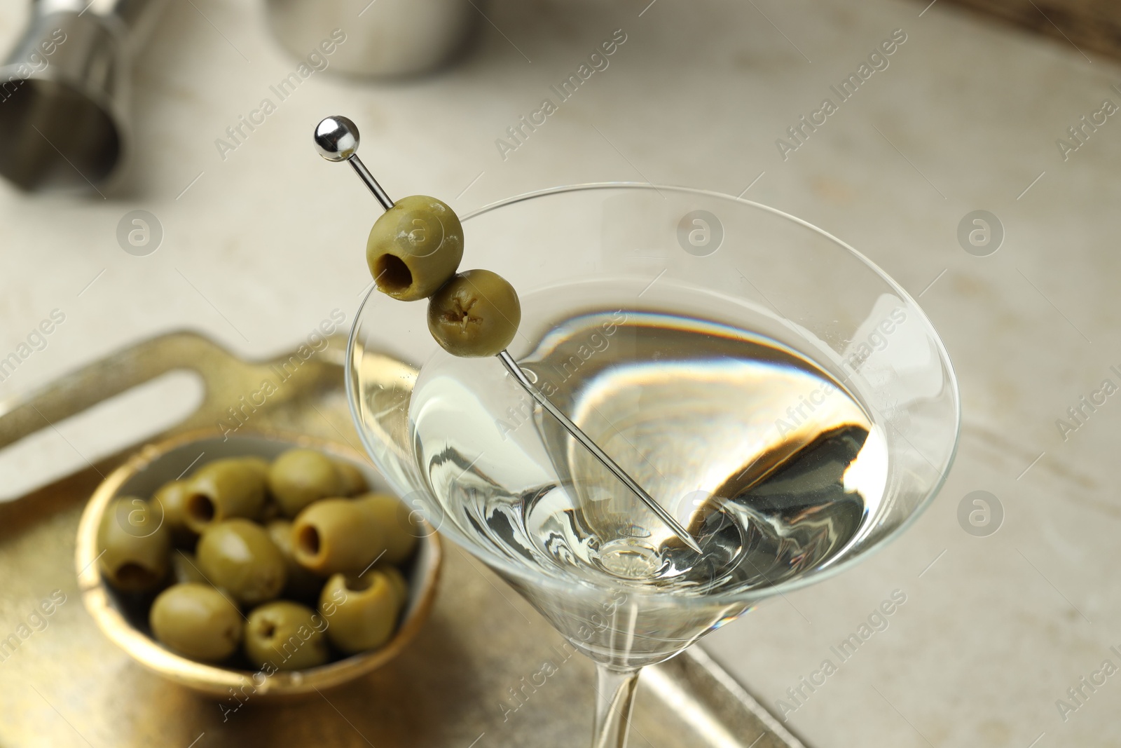 Photo of Martini cocktail with olives in glass on light table, closeup