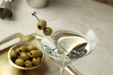 Photo of Martini cocktail with olives in glass on light table, closeup