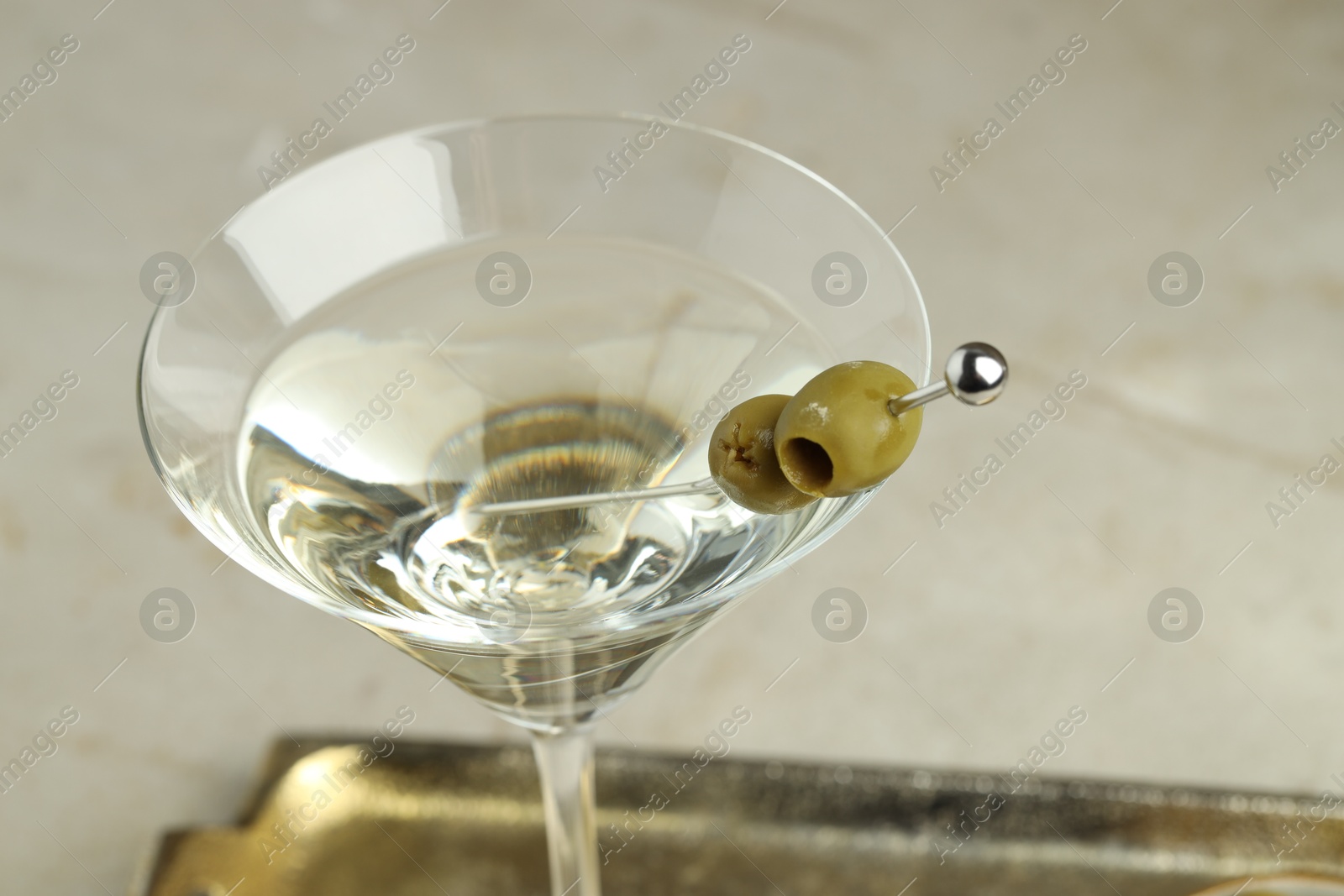 Photo of Martini cocktail with olives in glass on light table, closeup