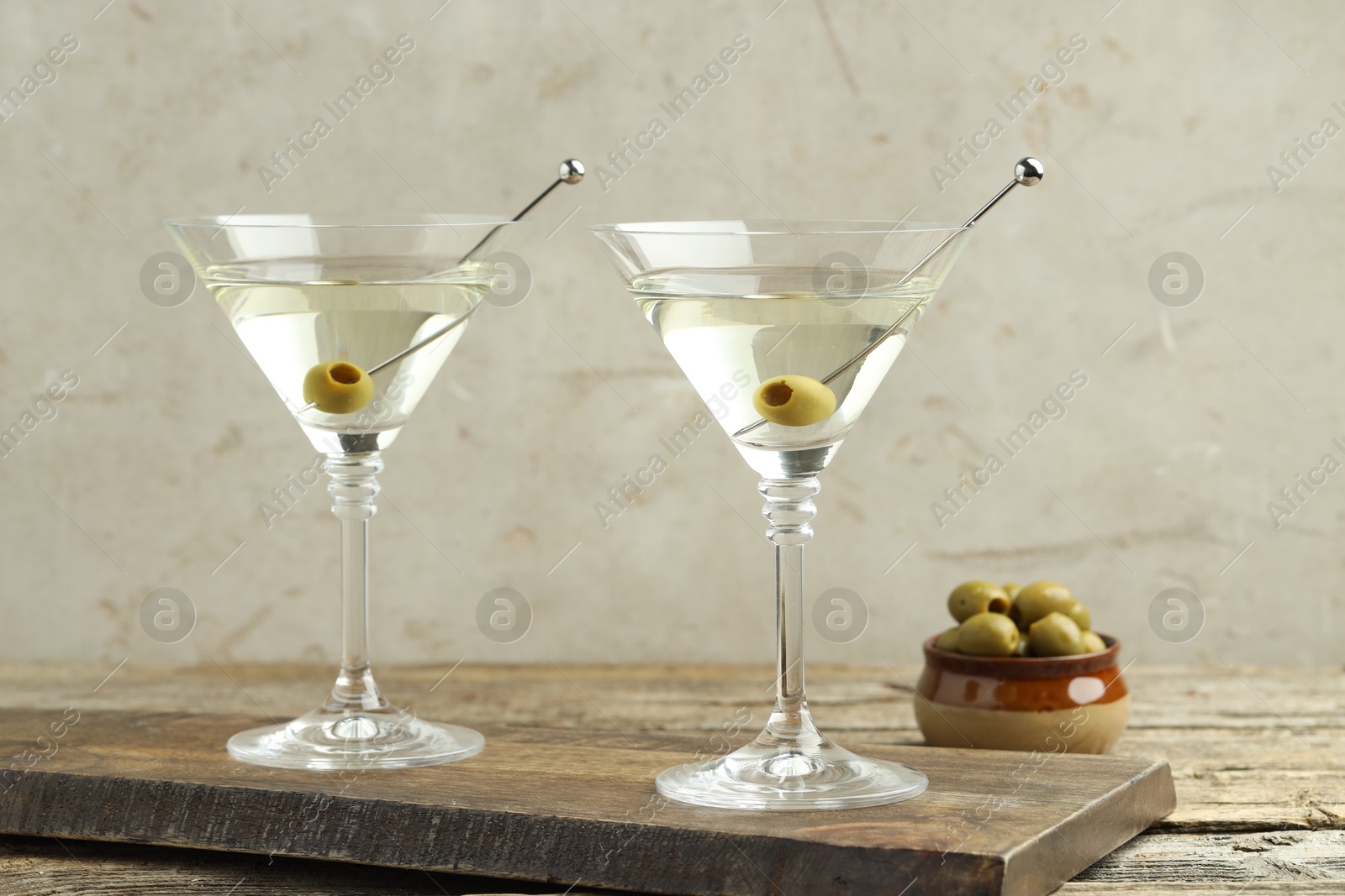 Photo of Martini cocktail with olives in glasses on wooden table