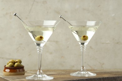 Photo of Martini cocktail with olives in glasses on wooden table