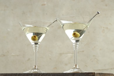 Photo of Martini cocktail with olives in glasses on wooden table