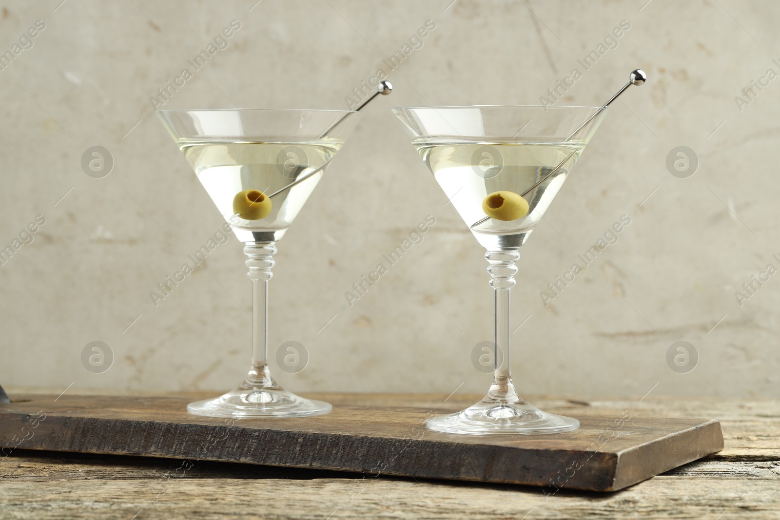 Photo of Martini cocktail with olives in glasses on wooden table