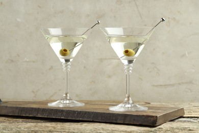 Photo of Martini cocktail with olives in glasses on wooden table