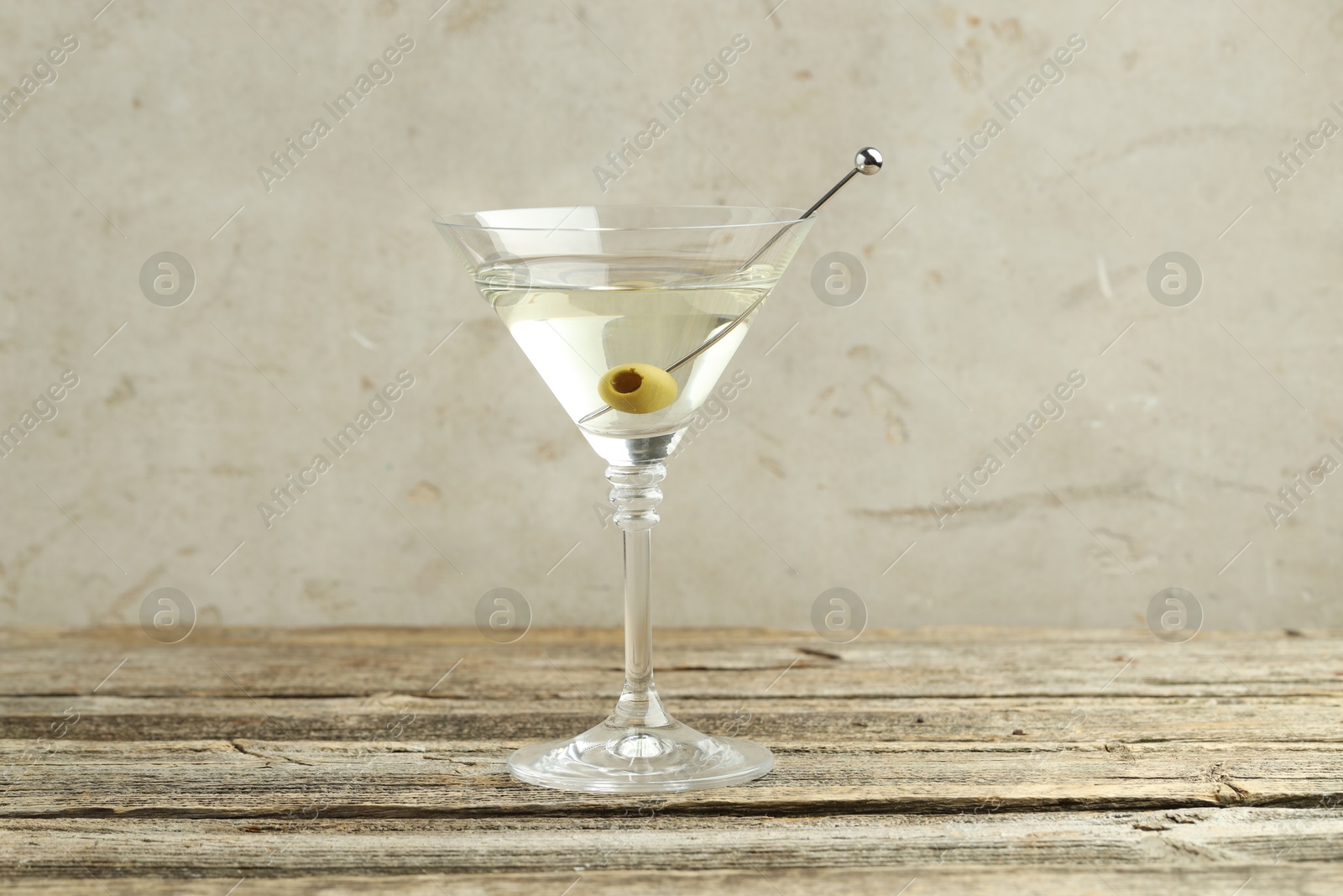 Photo of Martini cocktail with olive in glass on wooden table