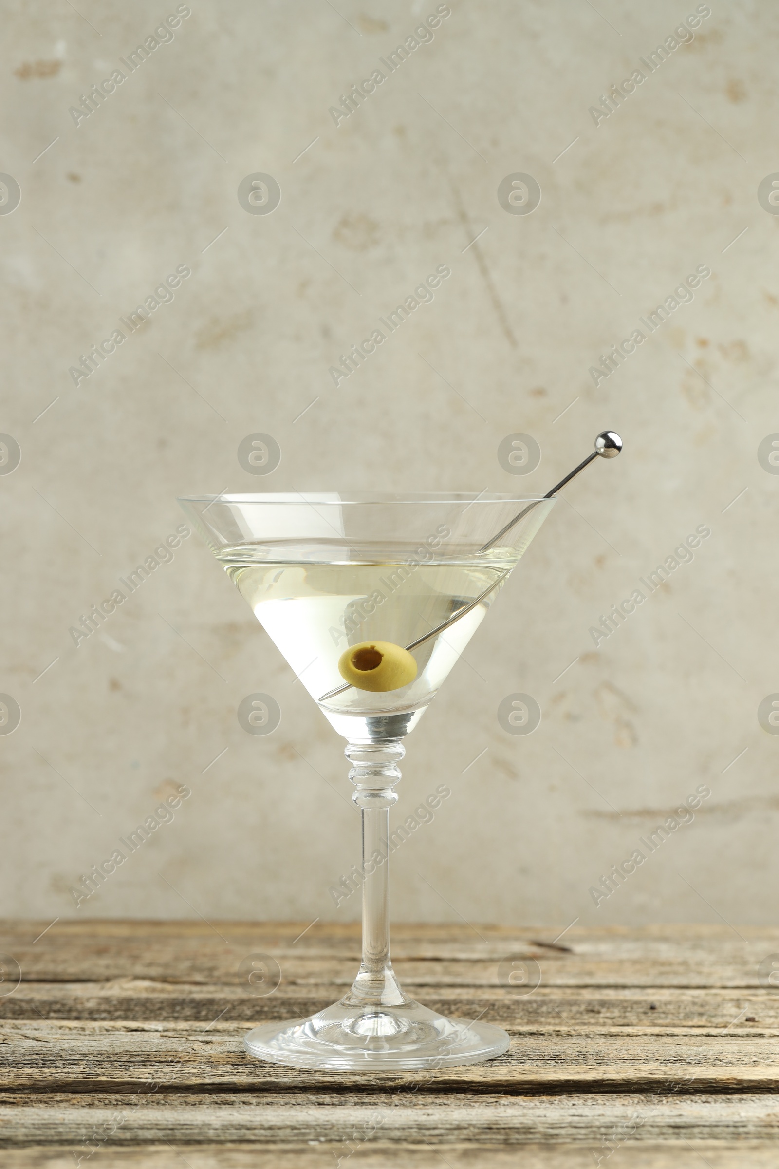 Photo of Martini cocktail with olive in glass on wooden table