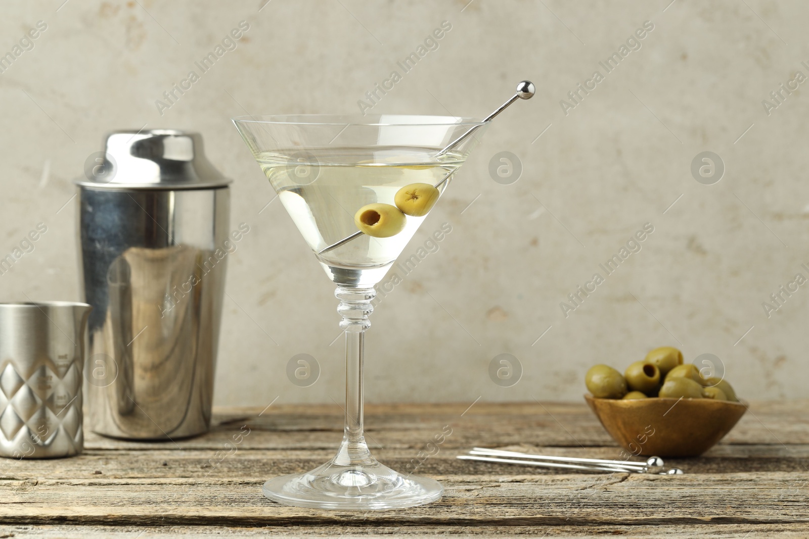 Photo of Martini cocktail with olives in glass and shaker on wooden table