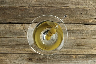 Photo of Martini cocktail with olives in glass on wooden table, top view